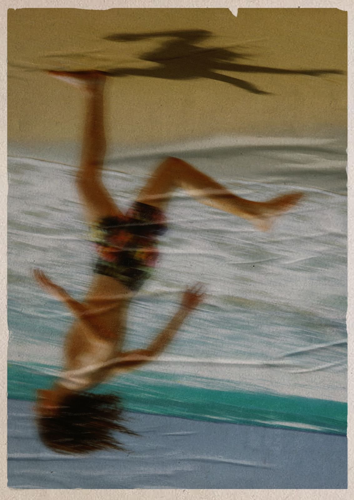 A printed photograph of a woman lying on a beach towel, shown upside down