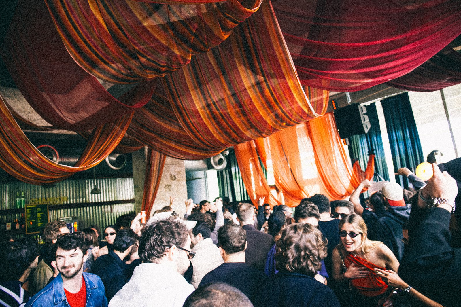 Daytime crowd dancing beneath the striped orange and red drapes