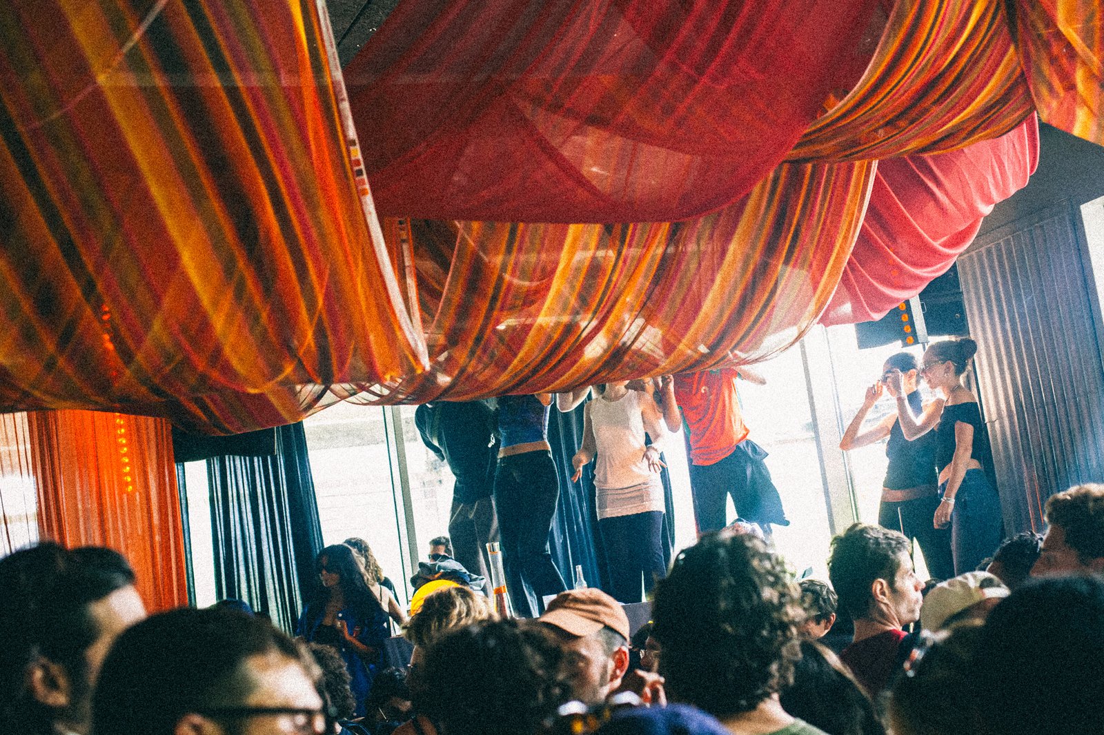 Drapes gathered into the ceiling above the crowd, daylight coming through the windows