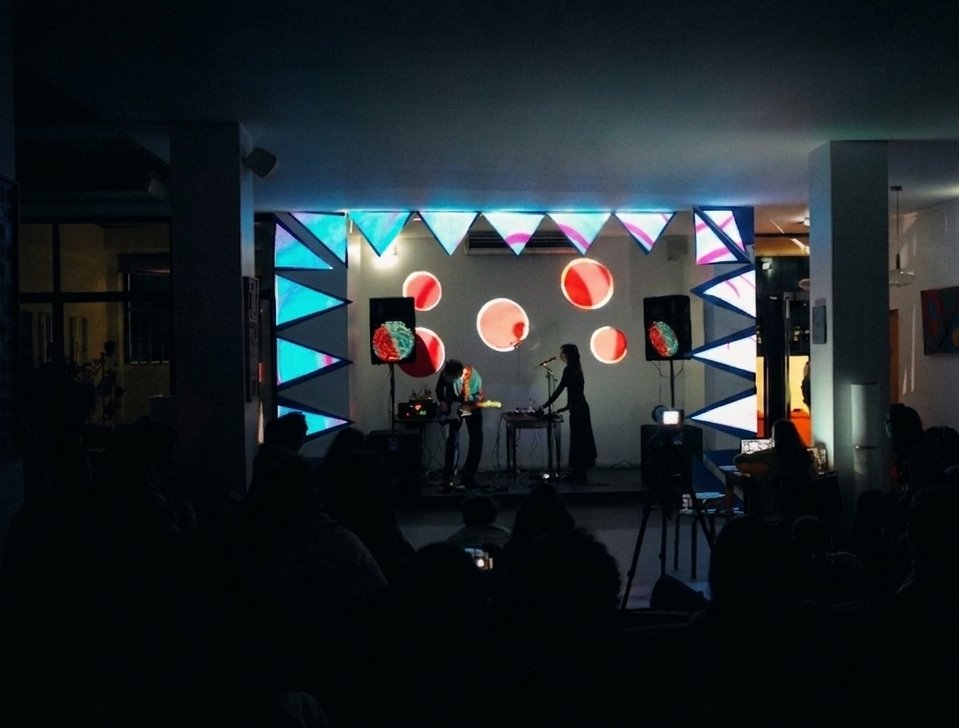Wide view of the courtyard venue at night, the lit stage seen between two pillars