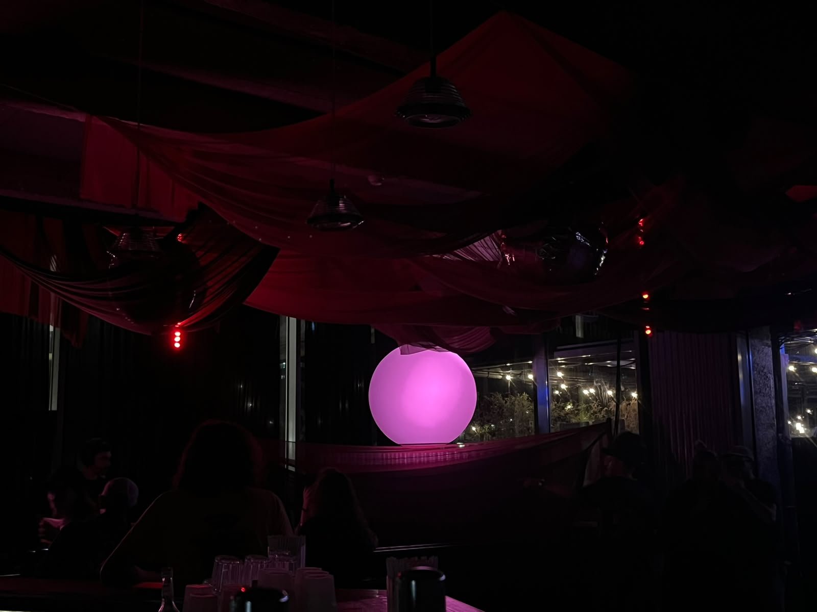 The terrace bar under red-lit drapes with the pink sphere in the window